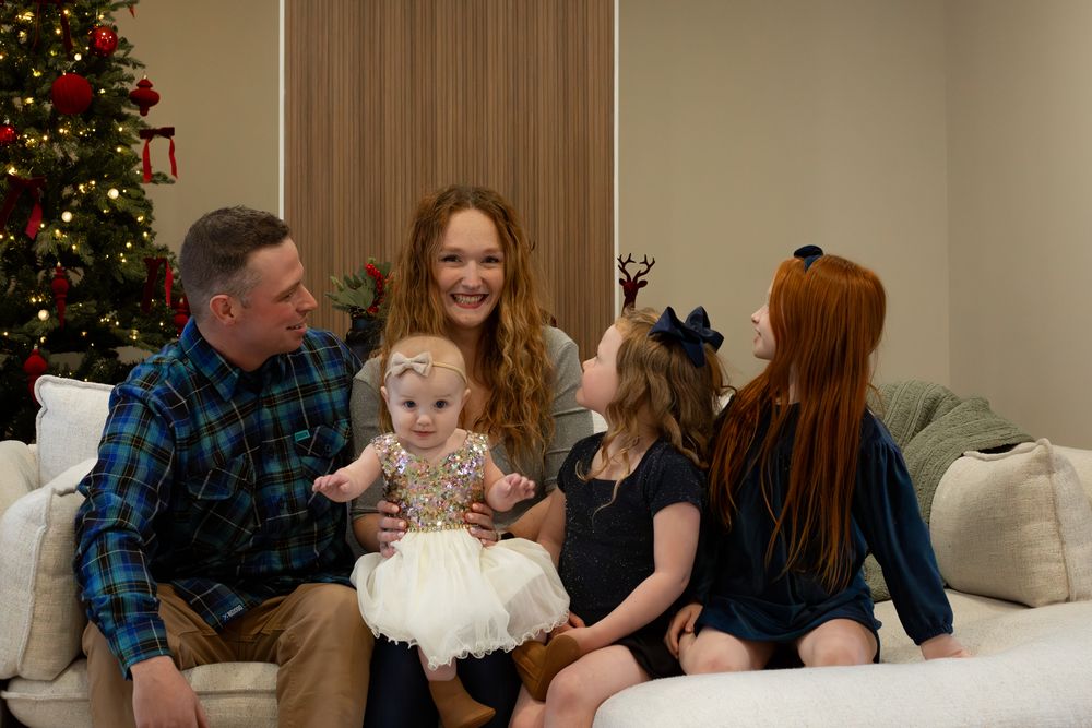 Candid family moment on couch during holiday season with Christmas tree visible.