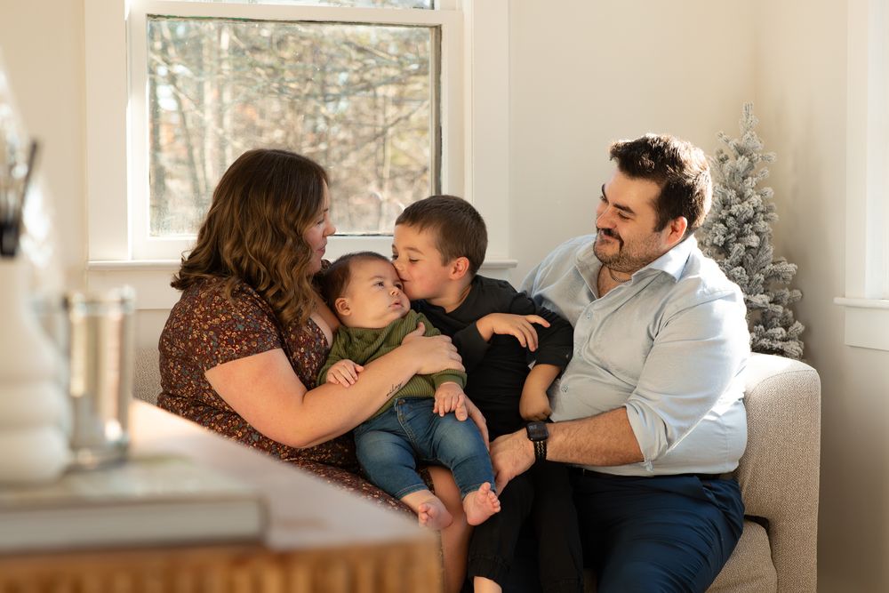 A couple shares an intimate moment together on a couch in a bright, sunlit living room.