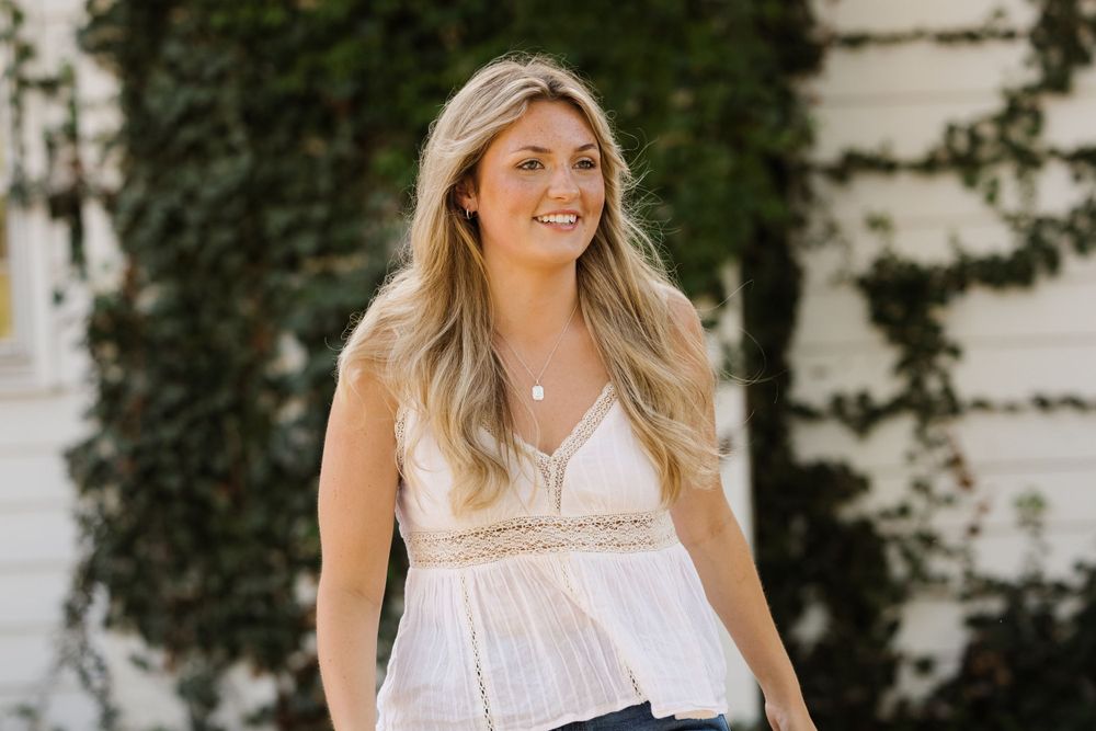Summer fashion portrait in white lace top and jeans against an ivy wall.