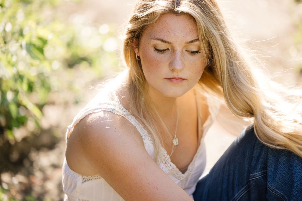 Soft portrait in white camisole against natural outdoor lighting.