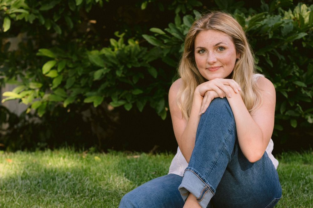 Casual outdoor portrait on grass wearing denim and white top.