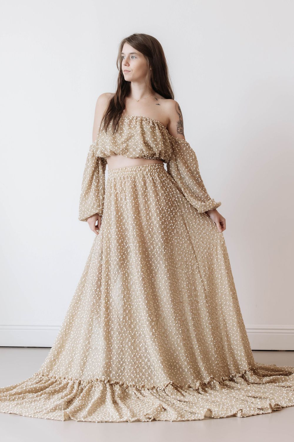 Woman wearing a boho off-shoulder gold lace two-piece set with long sleeves and a flowing maxi skirt.