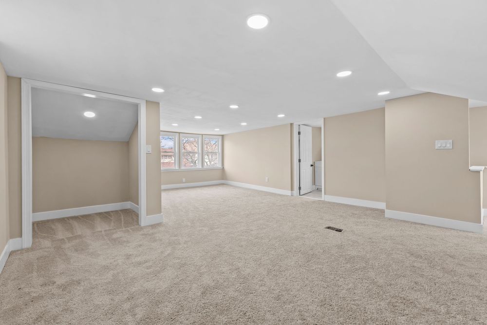 Spacious finished basement with neutral beige carpet, recessed lighting, and open layout ready for customization. Detroit Michigan