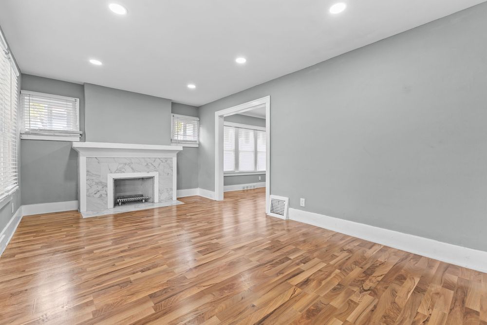 Bright living room with hardwood floors, white marble fireplace, recessed lighting, and neutral gray walls. Detroit Michigan