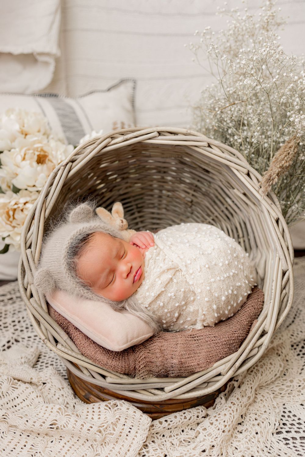 newborn photography session Sammamish WA  in a woven basket with baby's breath flowers and soft textiles.