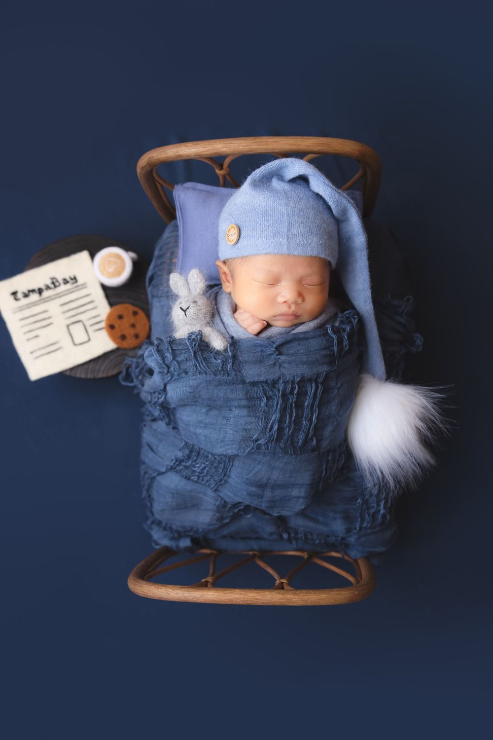 newborn photography session Sammamish  portrait with baby sleeping in blue outfit on wooden rocking chair with toy and name tag accessories.
