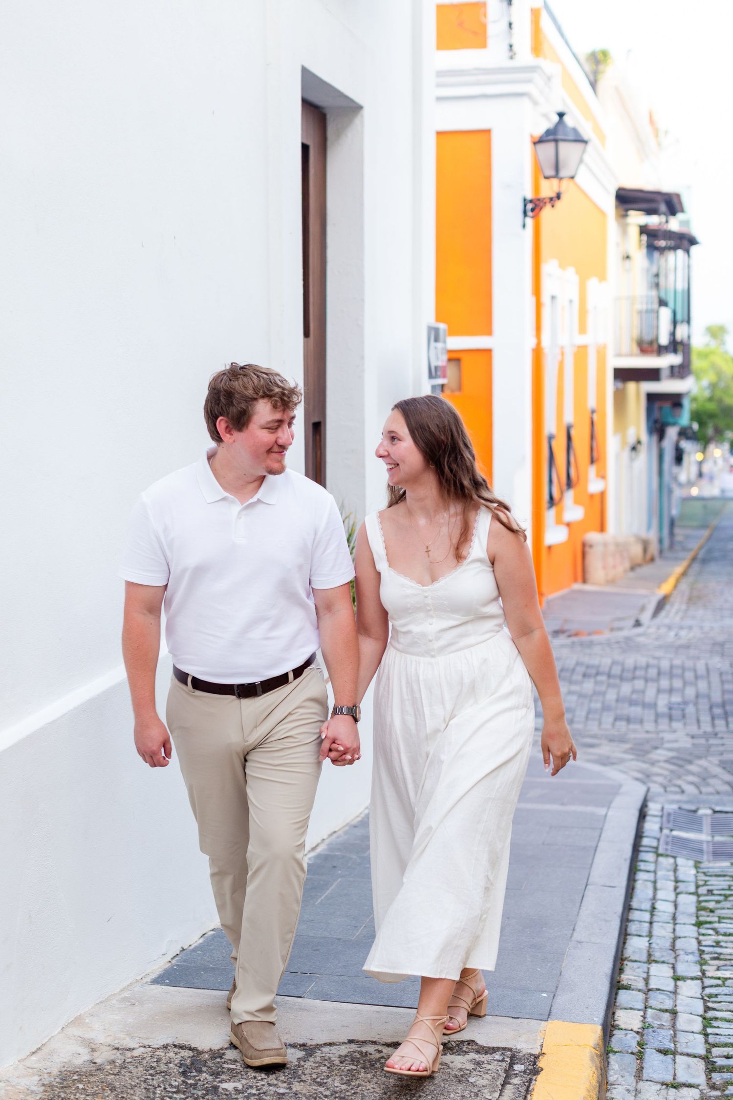 Couple walking on a sidewalk. Engagement photo session in Old San Juan, Puerto Rico.