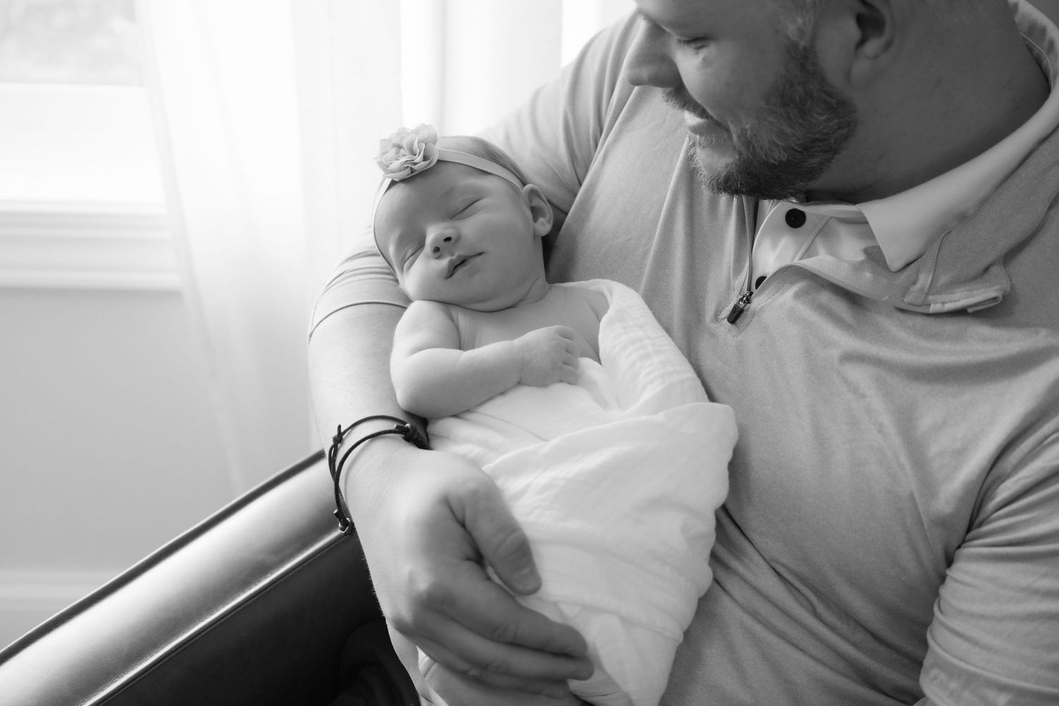 swaddled newborn baby asleep in dad's arms for in home newborn lifestyle session in lake elmo, mn