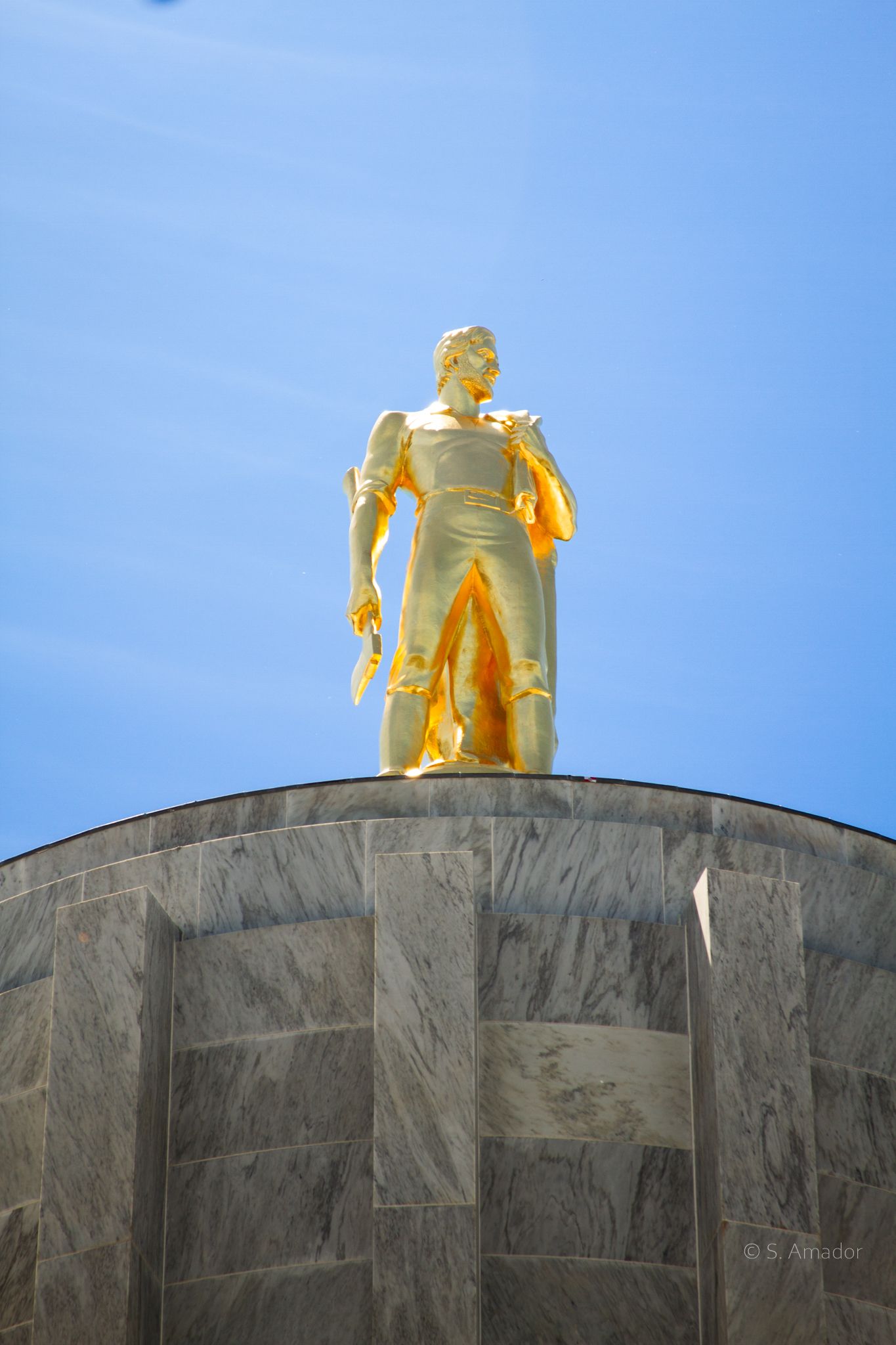 Golden pioneer statue atop the Oregon State Capitol dome against a clear blue sky in Salem, Oregon.