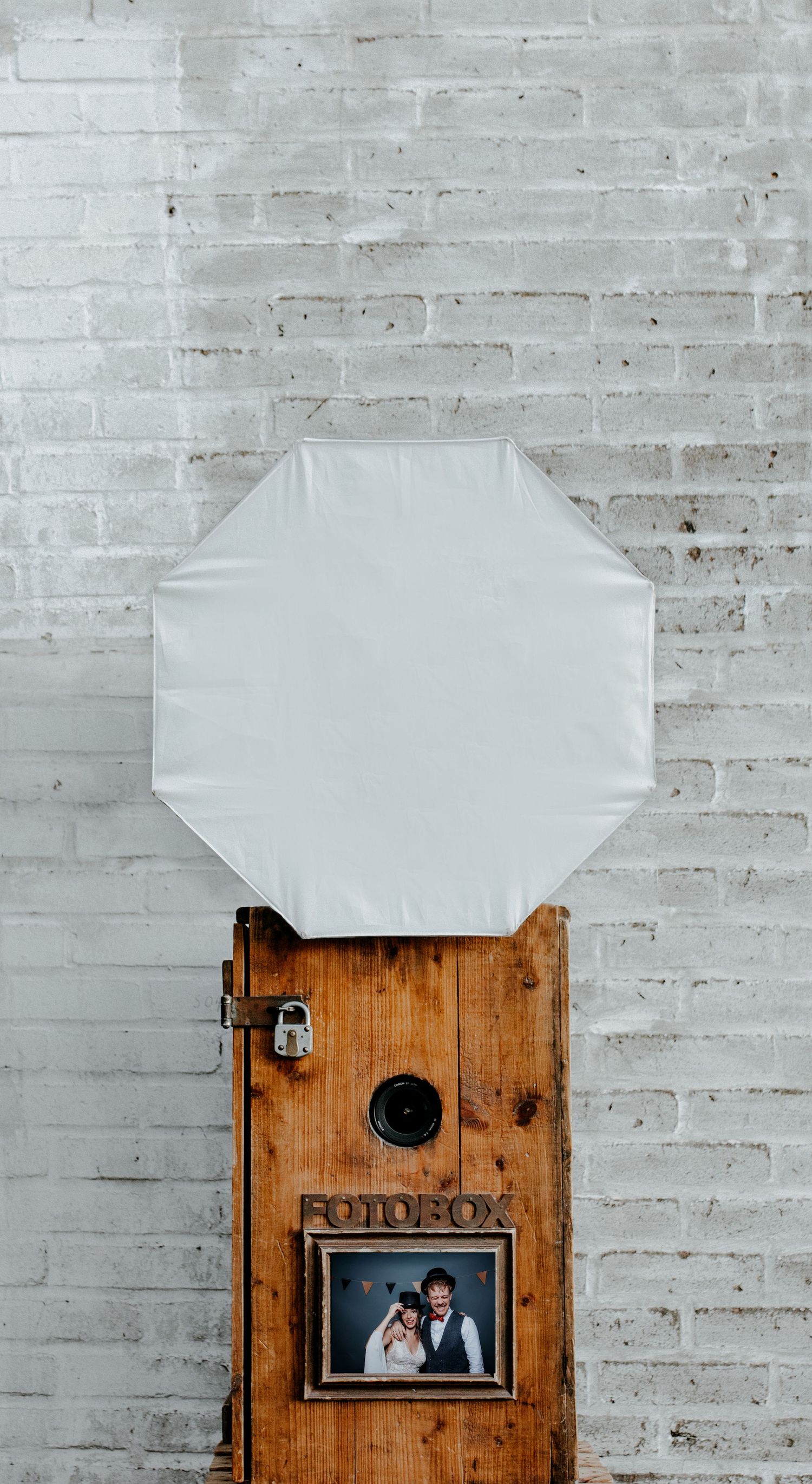 Artistic wedding photo composition with white paper against weathered brick wall and wooden mailbox.