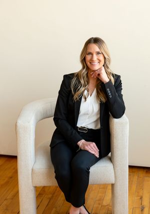 Professional portrait series featuring black blazer ensemble and white chair against hardwood floors.
