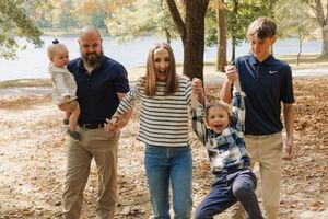 Family walking together and playing in autumn leaves on a sunny day in the park.