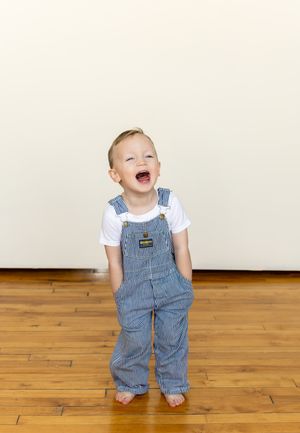 Series of photos showing a small child in overalls and white shirt playing on hardwood floors.