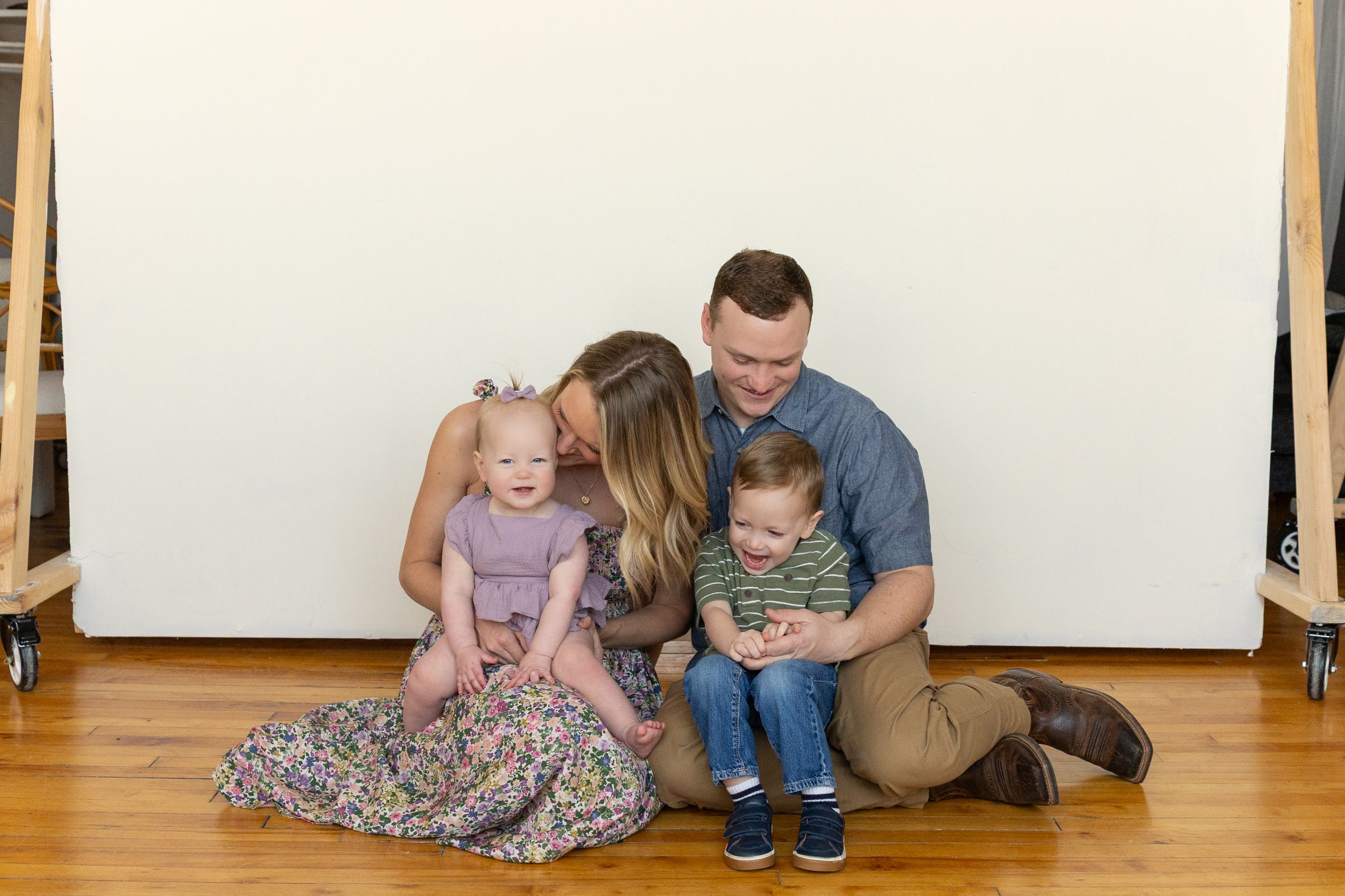 Parent and child sitting on wooden floor looking at tablet device together in home setting.