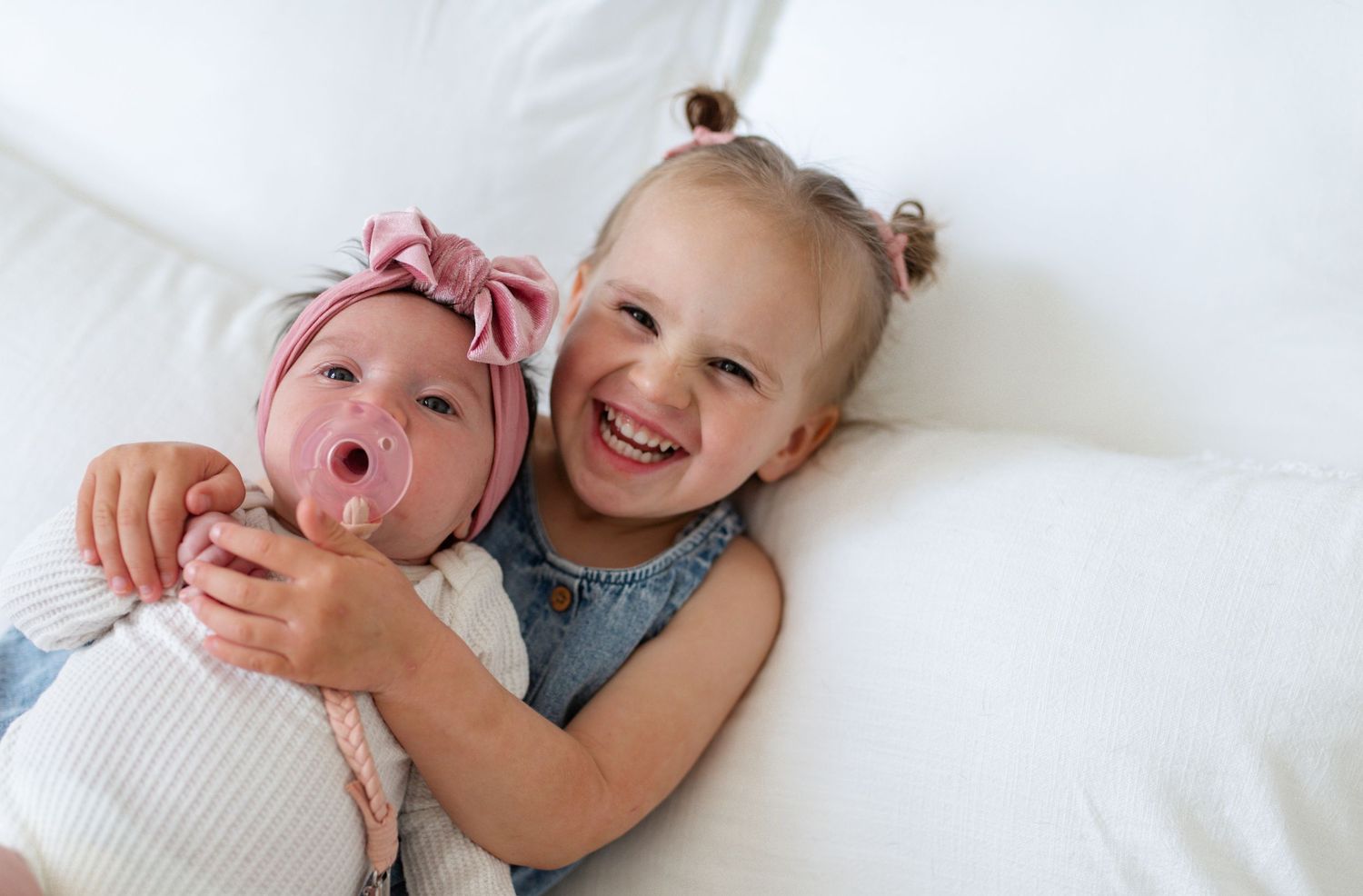 Toddler sibling and newborn baby lying together on a bed for St Charles County photography