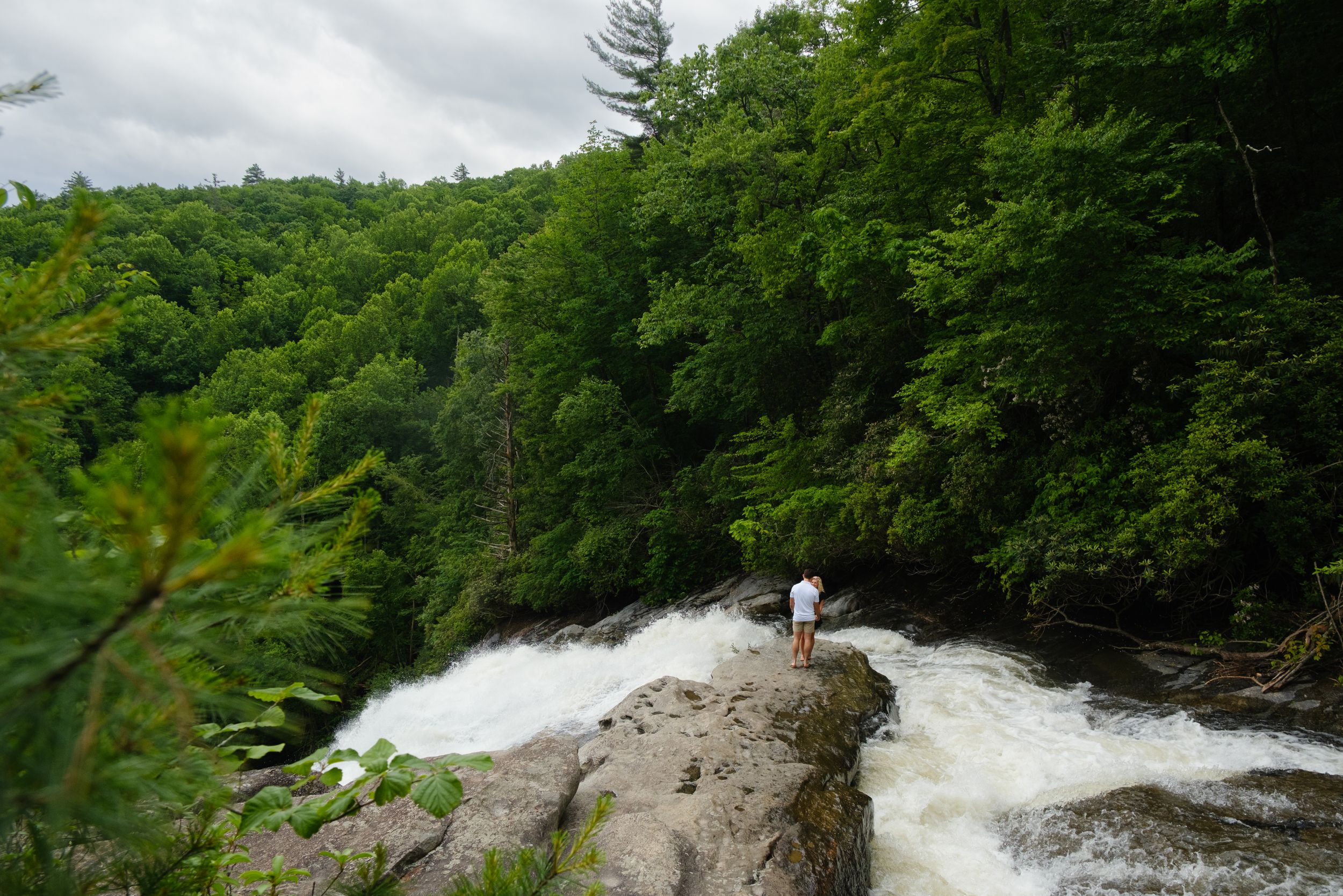 Couple celebrating engagement beside Rainbow Falls in Sapphire NC