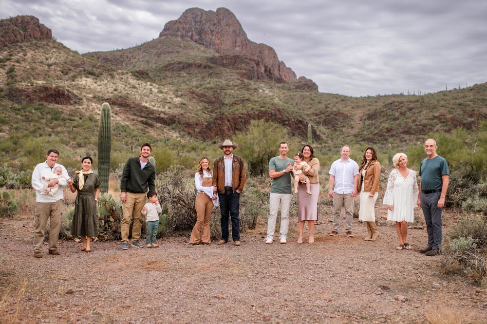Extended family group of eleven people poses together in an Arizona desert landscape with mountains.