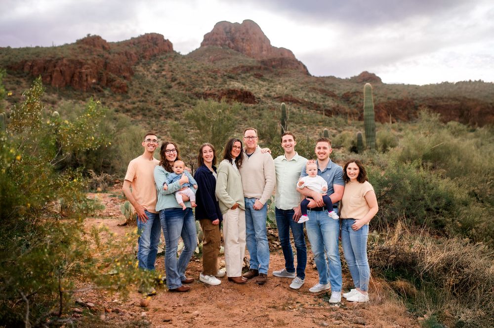 Large family group posing together in the Arizona desert with red rock mountains and cacti behind them.