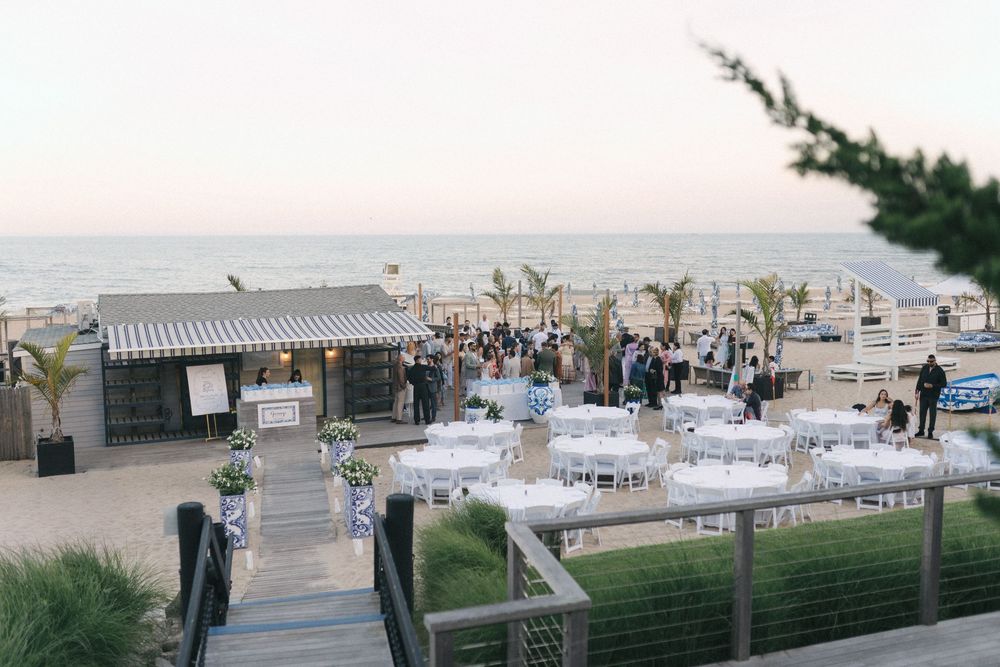 Elegant beachside wedding reception with white tables and ocean views at sunset.