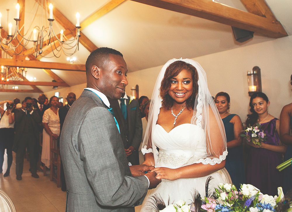 A joyful couple exchanges vows at their wedding ceremony, bride in white gown with veil, groom in gray suit.