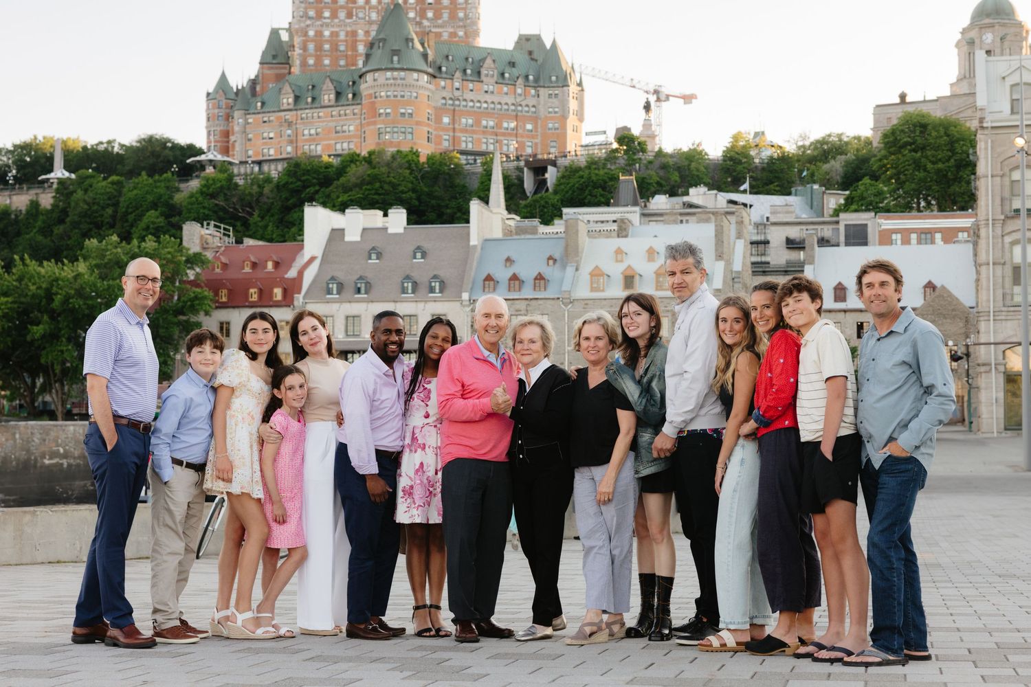 Large family group posing together outdoors with Chateau Frontenac and Quebec City skyline in background.