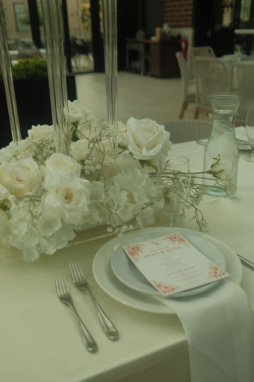 Elegant wedding reception table with white roses, hydrangeas, and personalized menu card place setting.