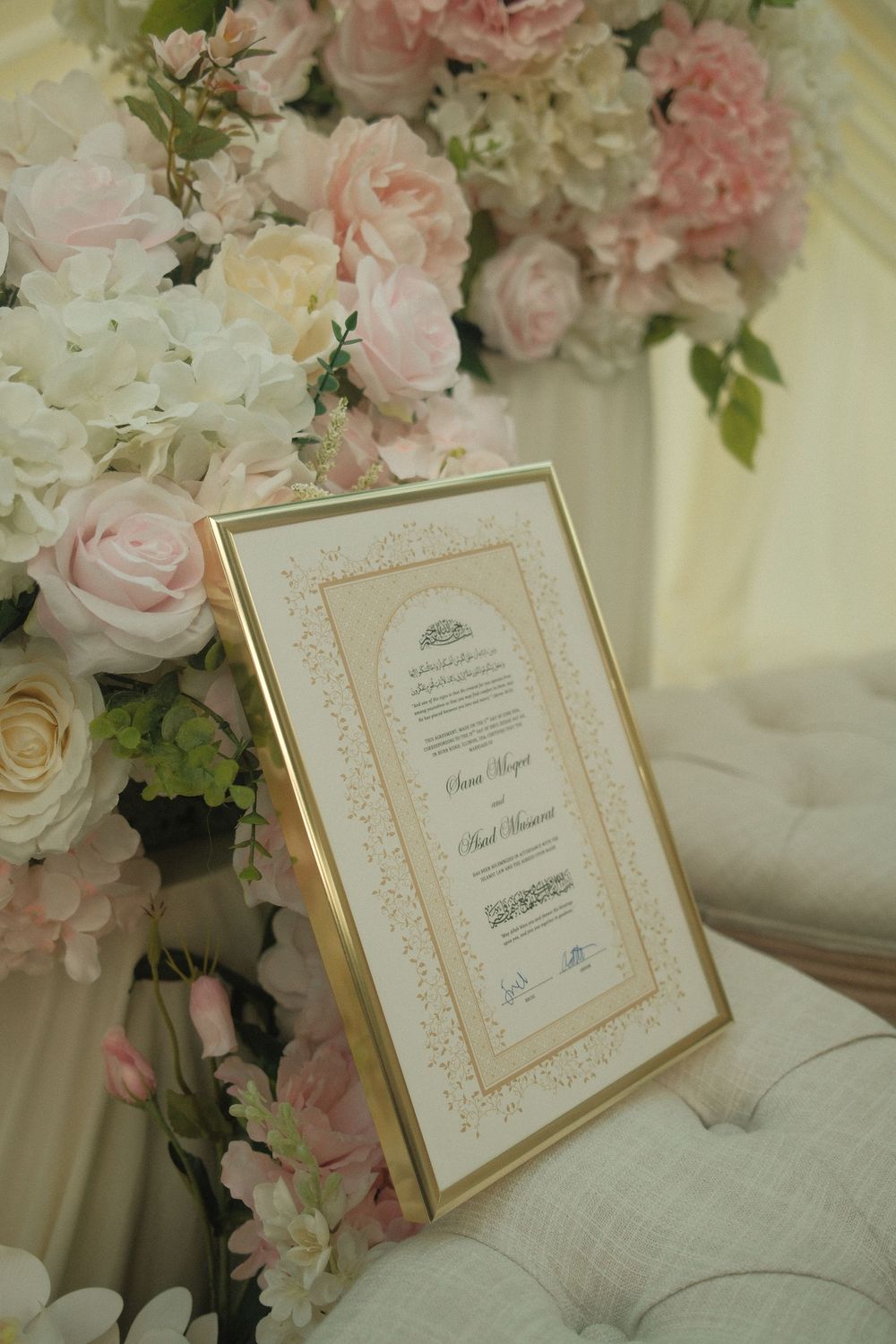 Framed Islamic Nikkah marriage certificate displayed beside pink and white floral wedding arrangement.