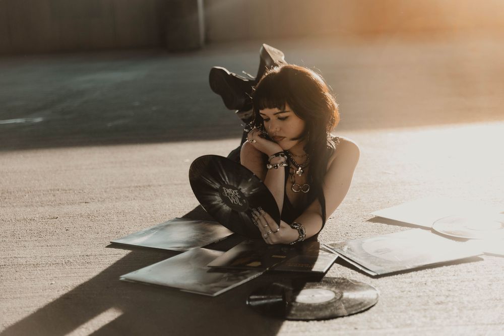Girl lays on vinyl albums for moody, cinematic, urban, portrait, senior photos in Denver, Colorado outside, urban, and nature photos