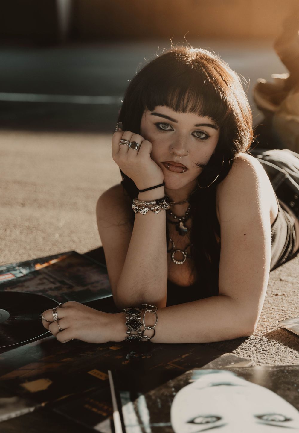 Girl lays on vinyl albums for moody, cinematic, urban, portrait, senior photos in Denver, Colorado outside, urban, and nature photos