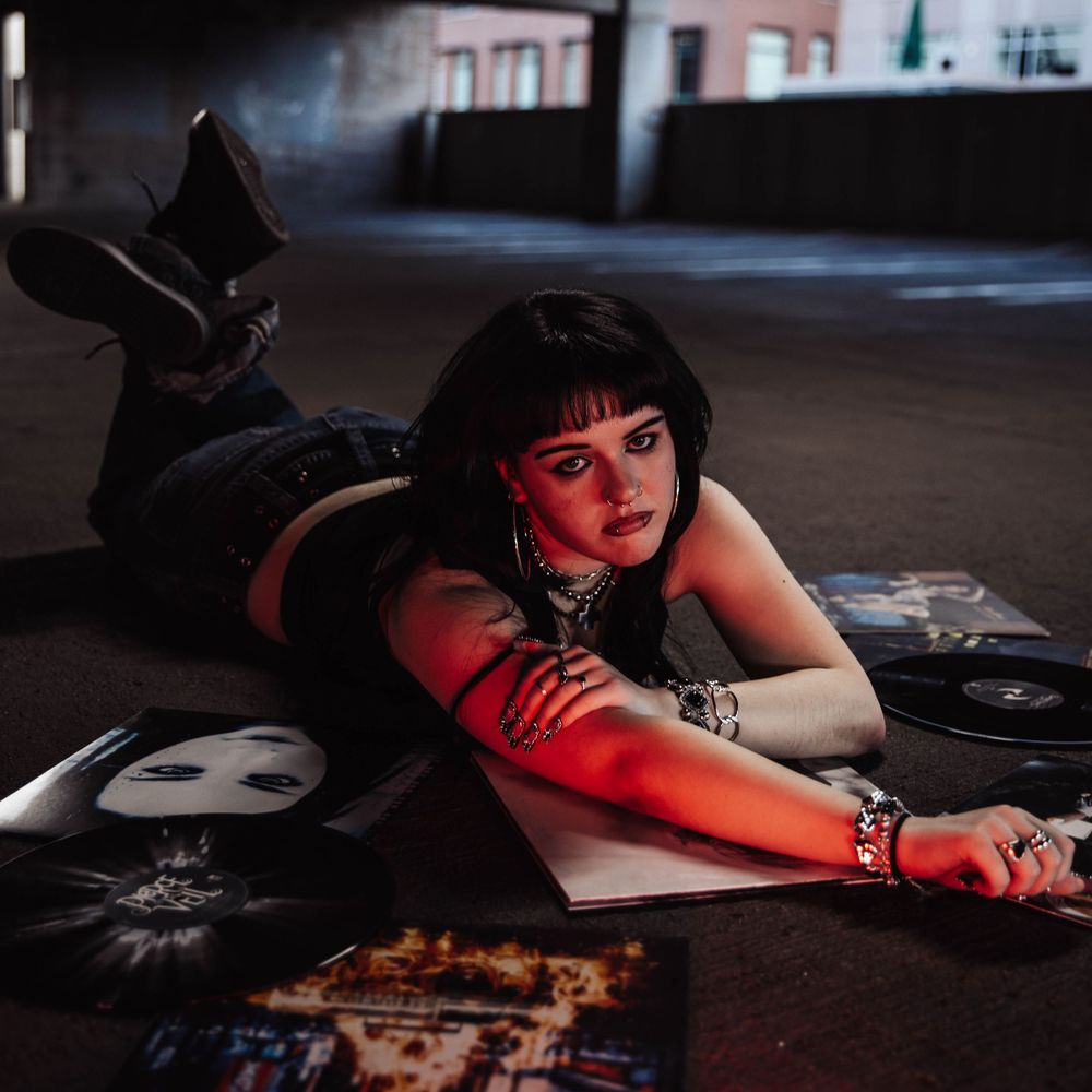 Girl lays on vinyl albums for moody, cinematic, urban, portrait, senior photos in Denver, Colorado outside, urban, and nature photos