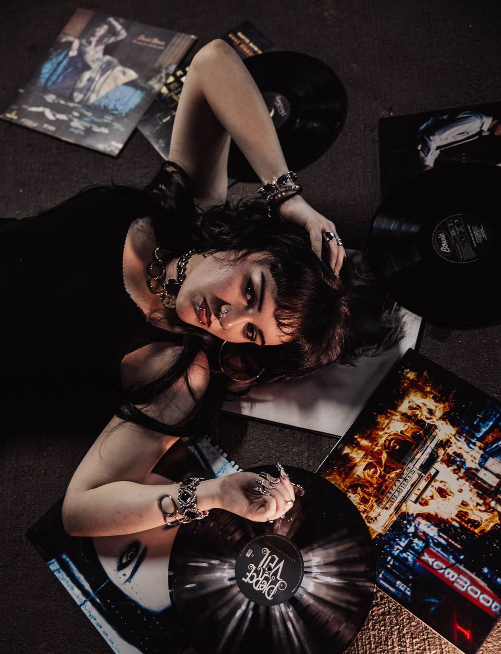Girl lays on vinyl albums for moody, cinematic, urban, portrait, senior photos in Denver, Colorado outside, urban, and nature photos