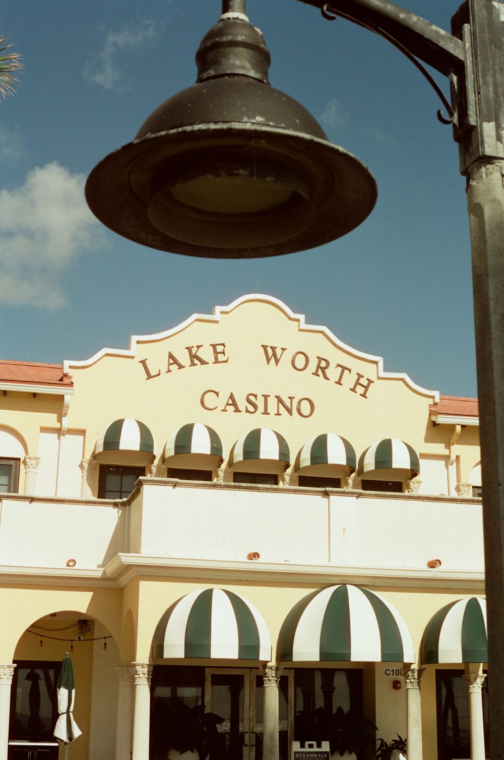 Lake Worth Casino building facade with striped awnings and vintage street lamp in Florida.