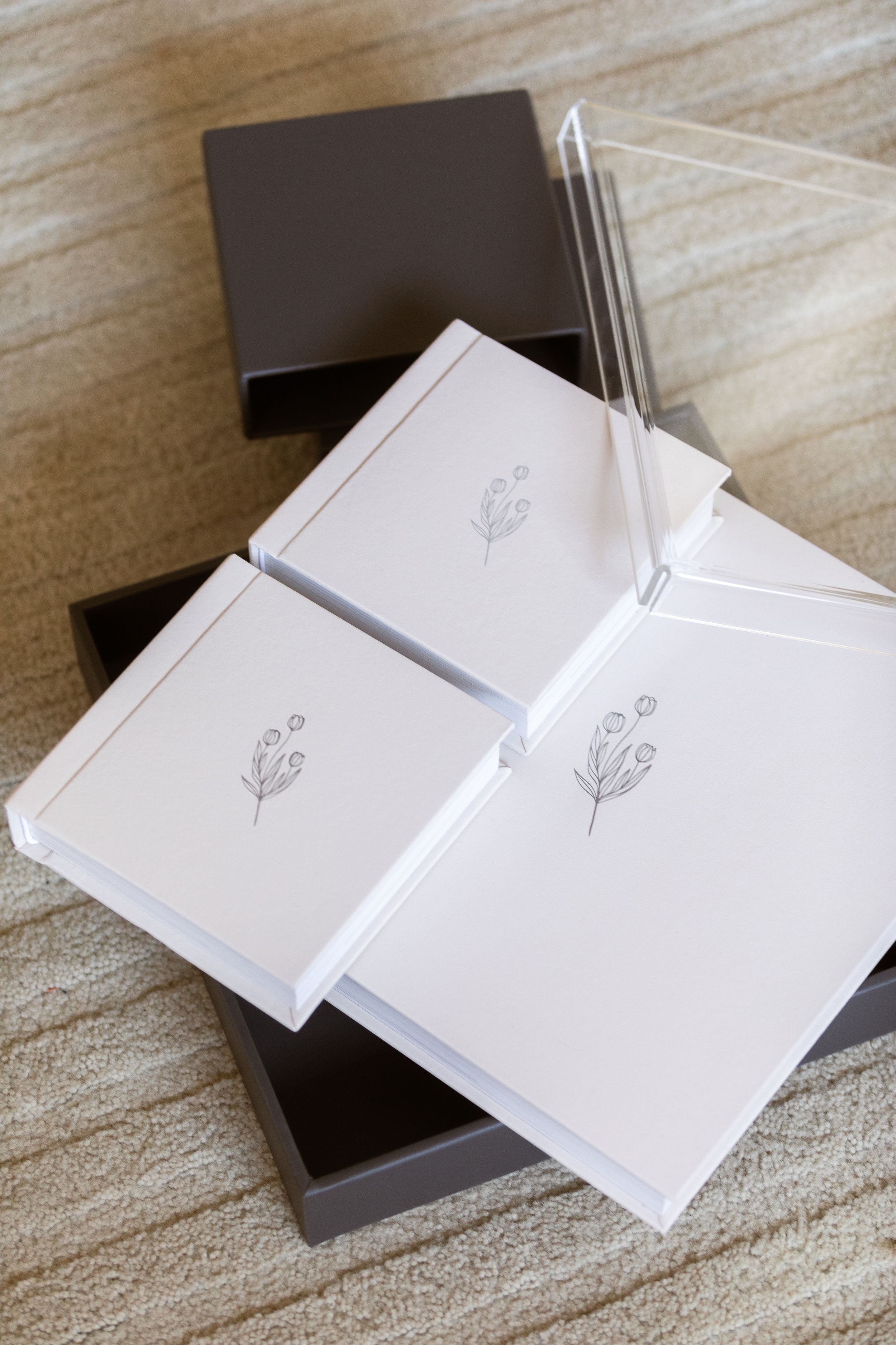 Several minimalist white cards featuring delicate line drawings of flowers lay on top of a dark brown box.