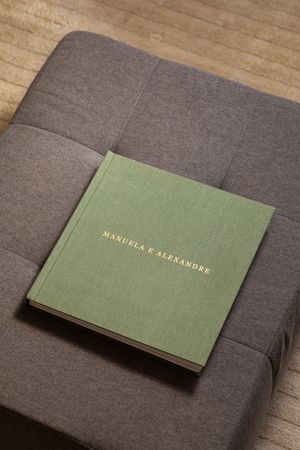 Minimal green cloth-bound books with gold text embossed on covers displayed on gray fabric surface.
