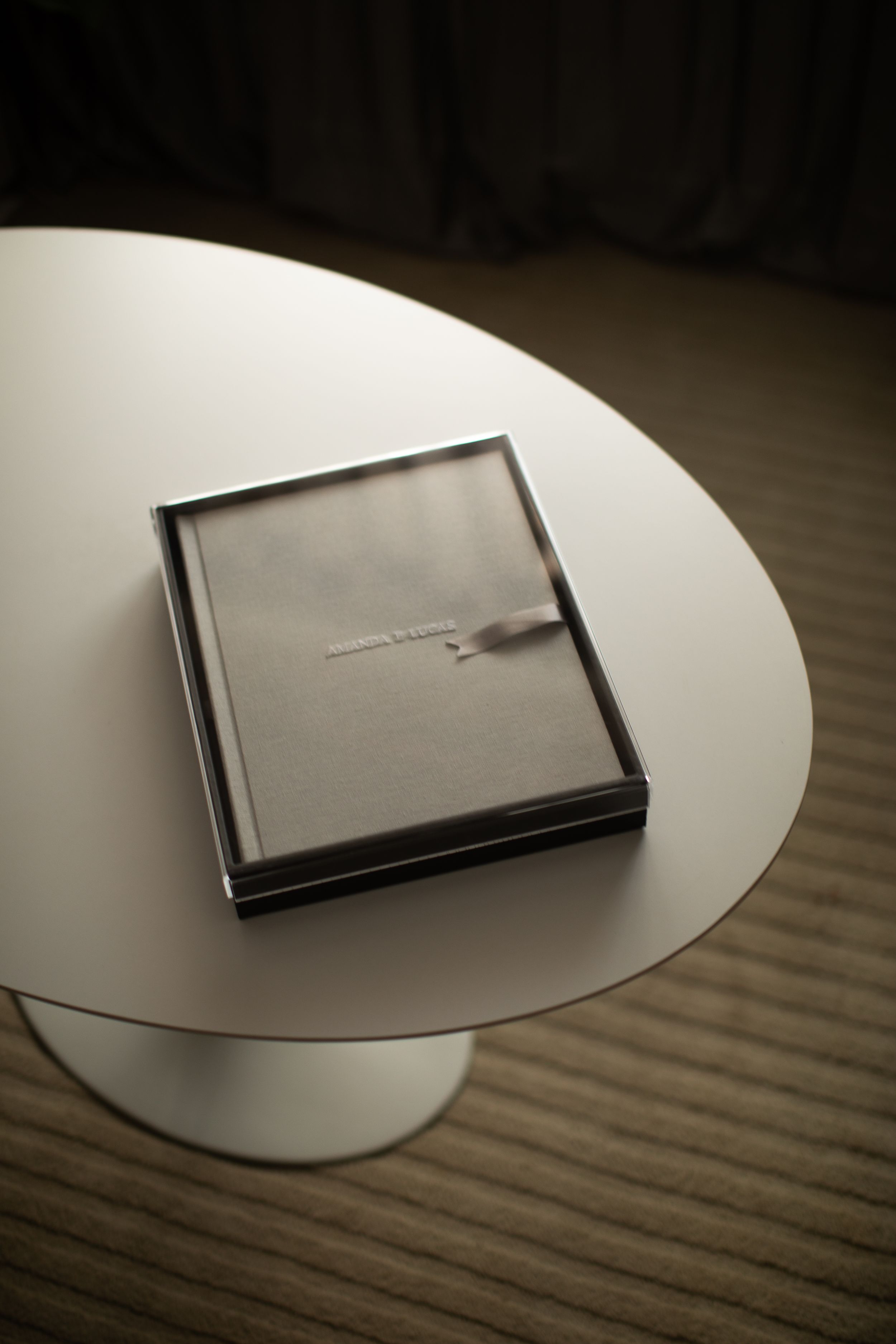 A series of minimalist photos showing a small dark square object on a white circular surface against wood grain background.