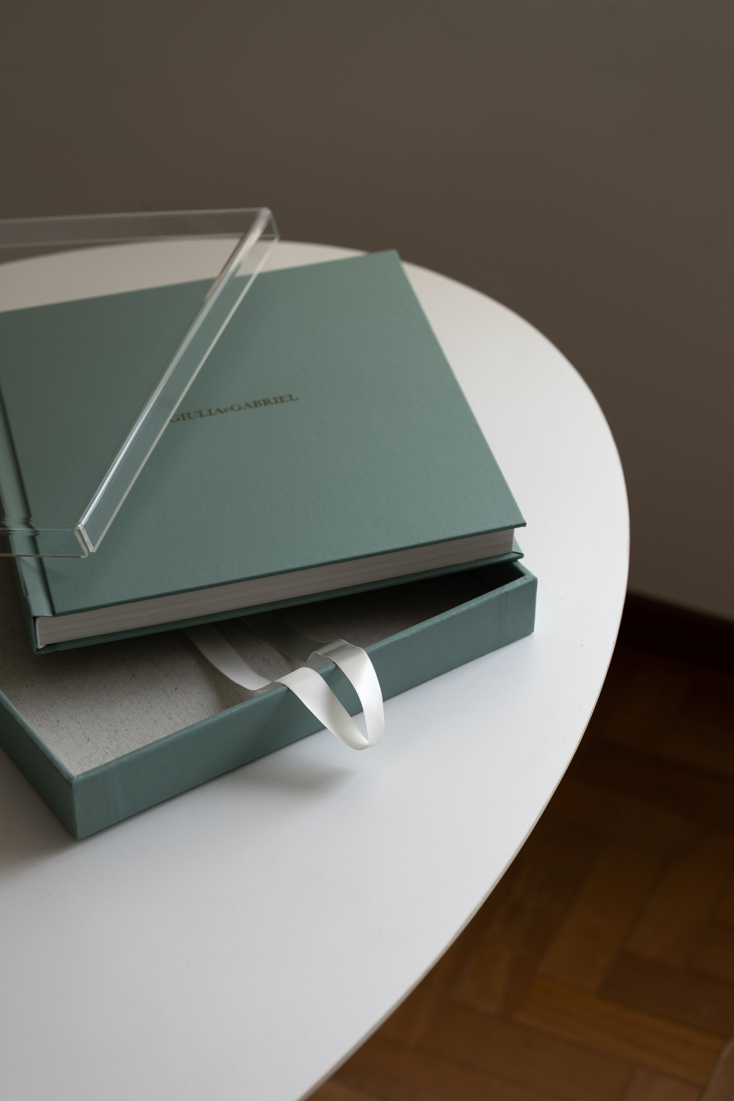 Close-up photos showing a minimalist gray portfolio book displayed on a white surface at different angles.