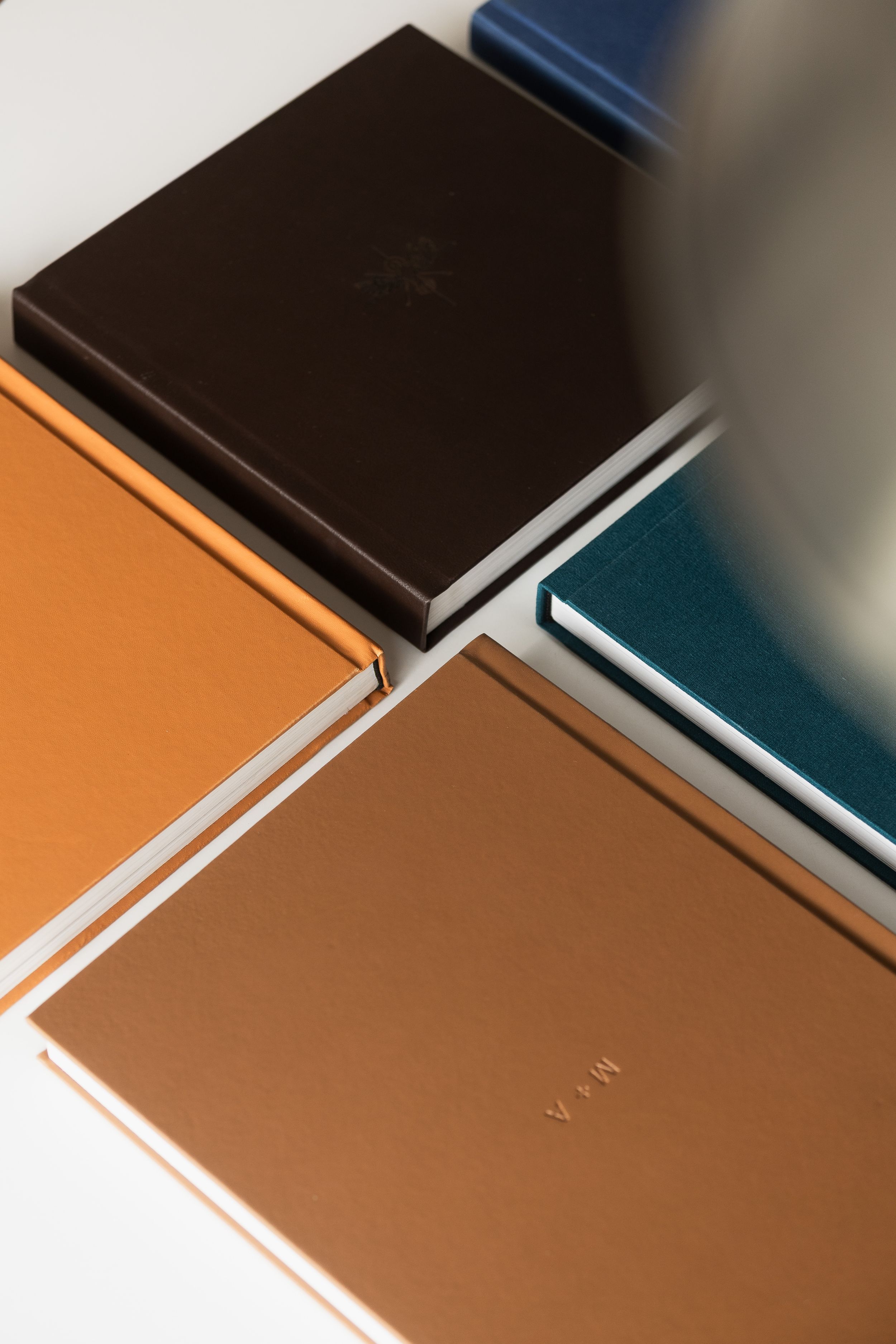 Collection of leather-bound notebooks and journals in brown, orange, and teal arranged on a white surface.