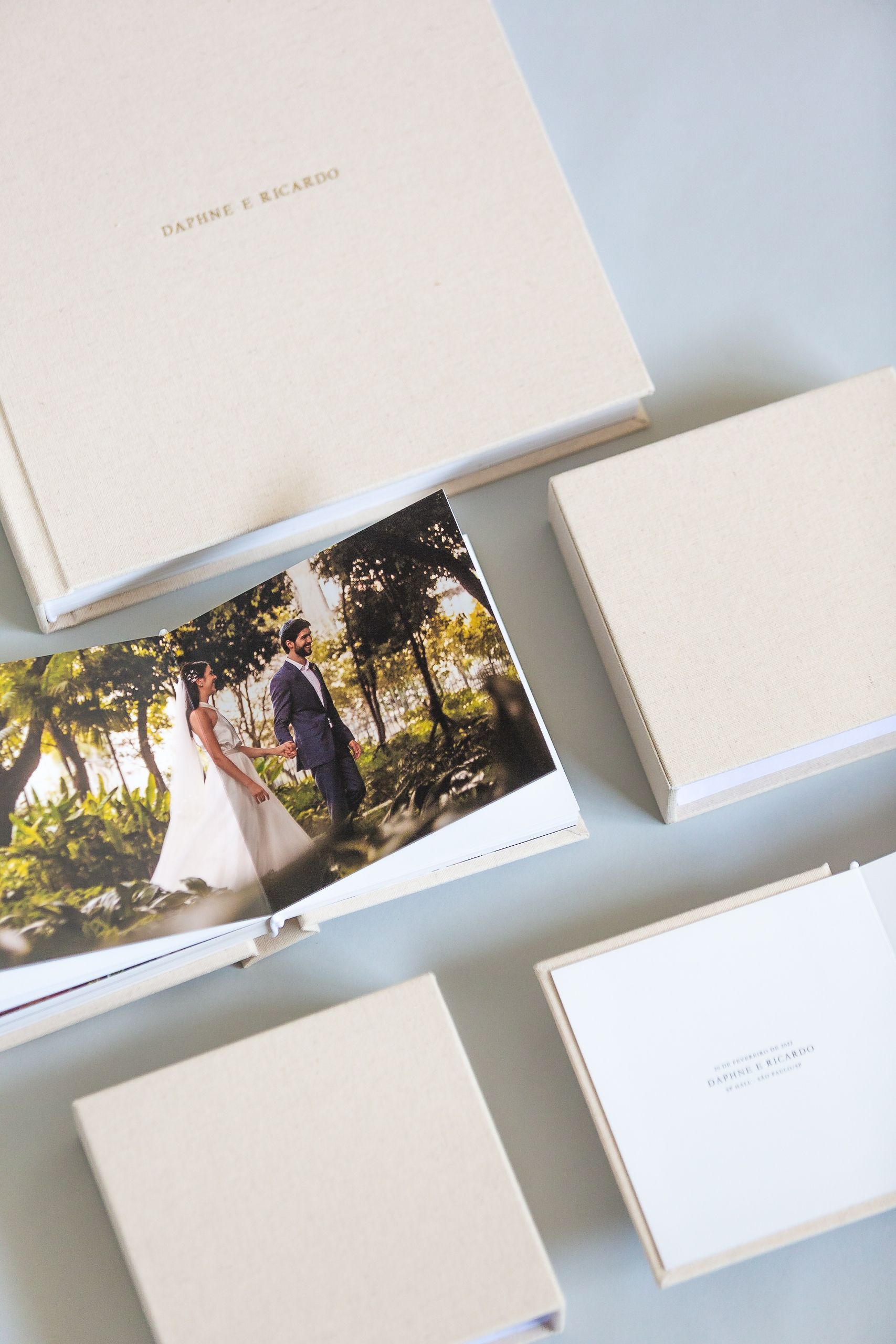 Elegant wedding photo album boxes in cream white with a romantic outdoor photograph peeking out from one box.