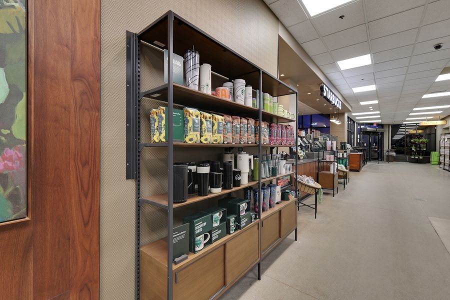 Metal shelving units stocked with Starbucks products and merchandise lining a retail store aisle.