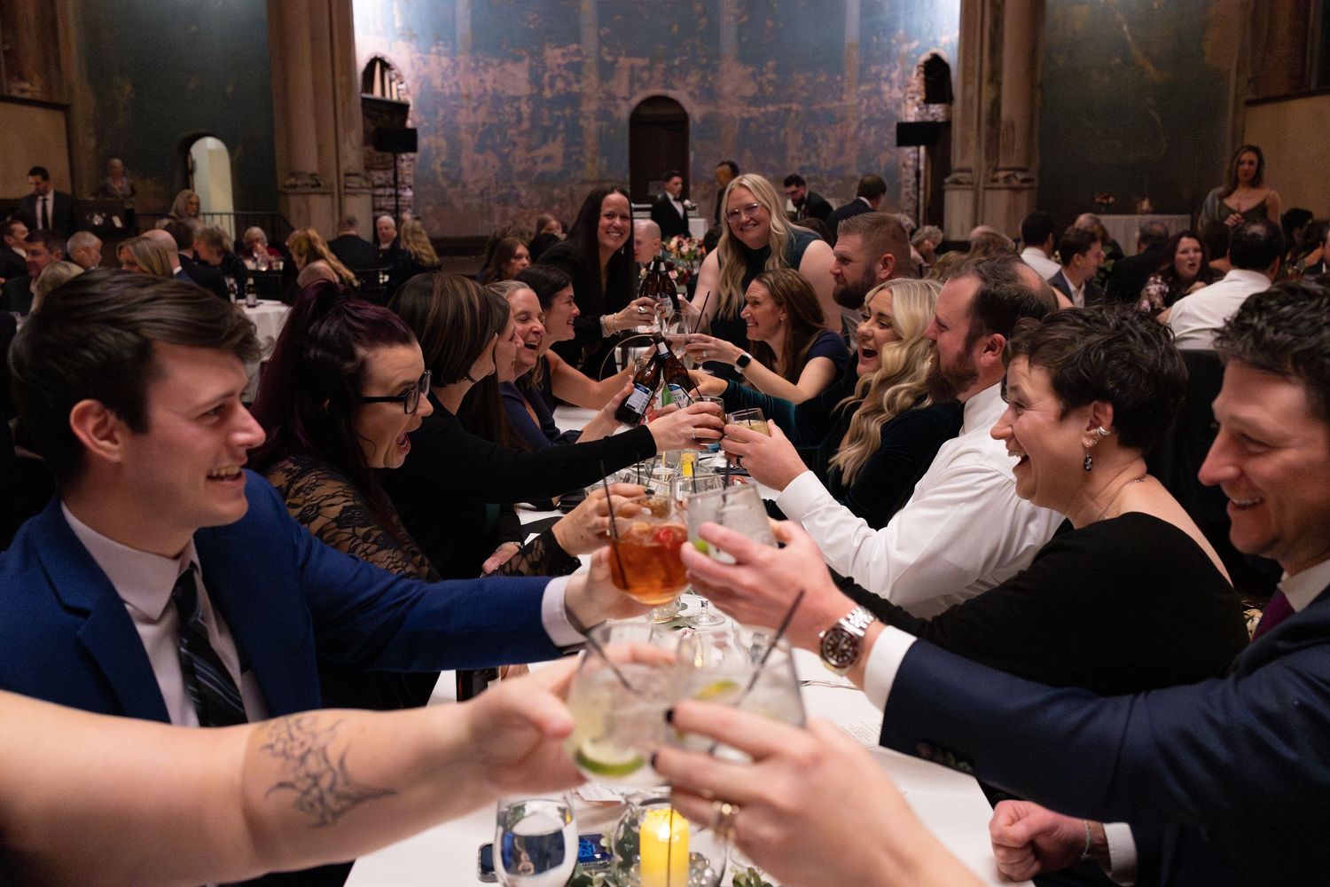 Group of elegantly dressed guests toasting drinks at a wedding reception at the Monastery Cincinnati wedding venue.