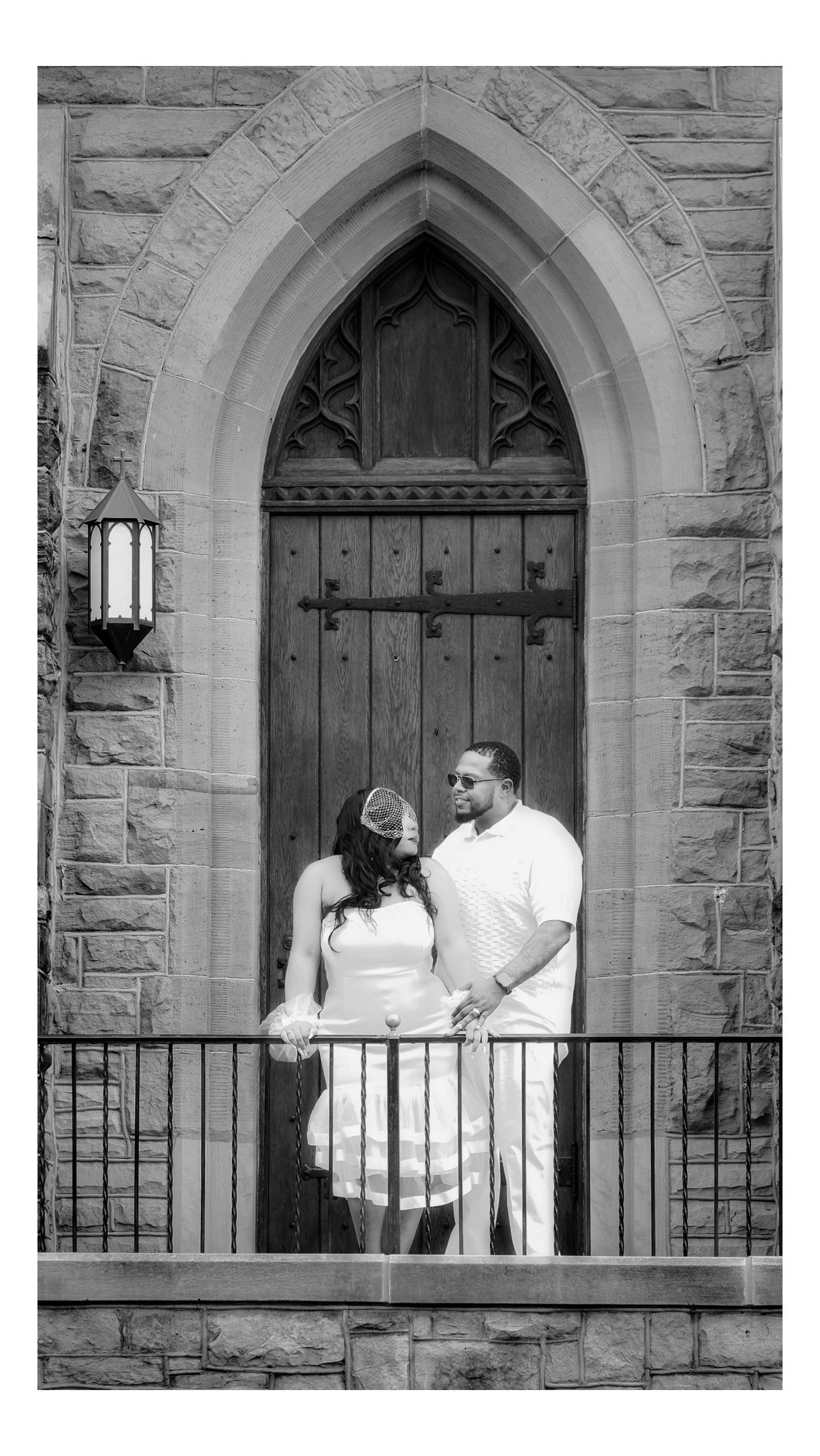 A romantic couple in white stands on a balcony by Ellucid Design Studio LLC Great Lakes Bay Region