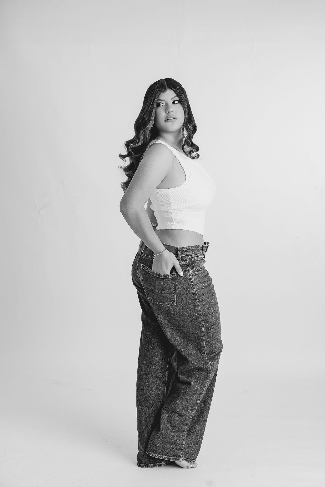 Fotógrafa en ropa casual trabajando en su laptop, rodeada de lentes y equipo profesional, reflejando pasión y dedicación por la fotografía.