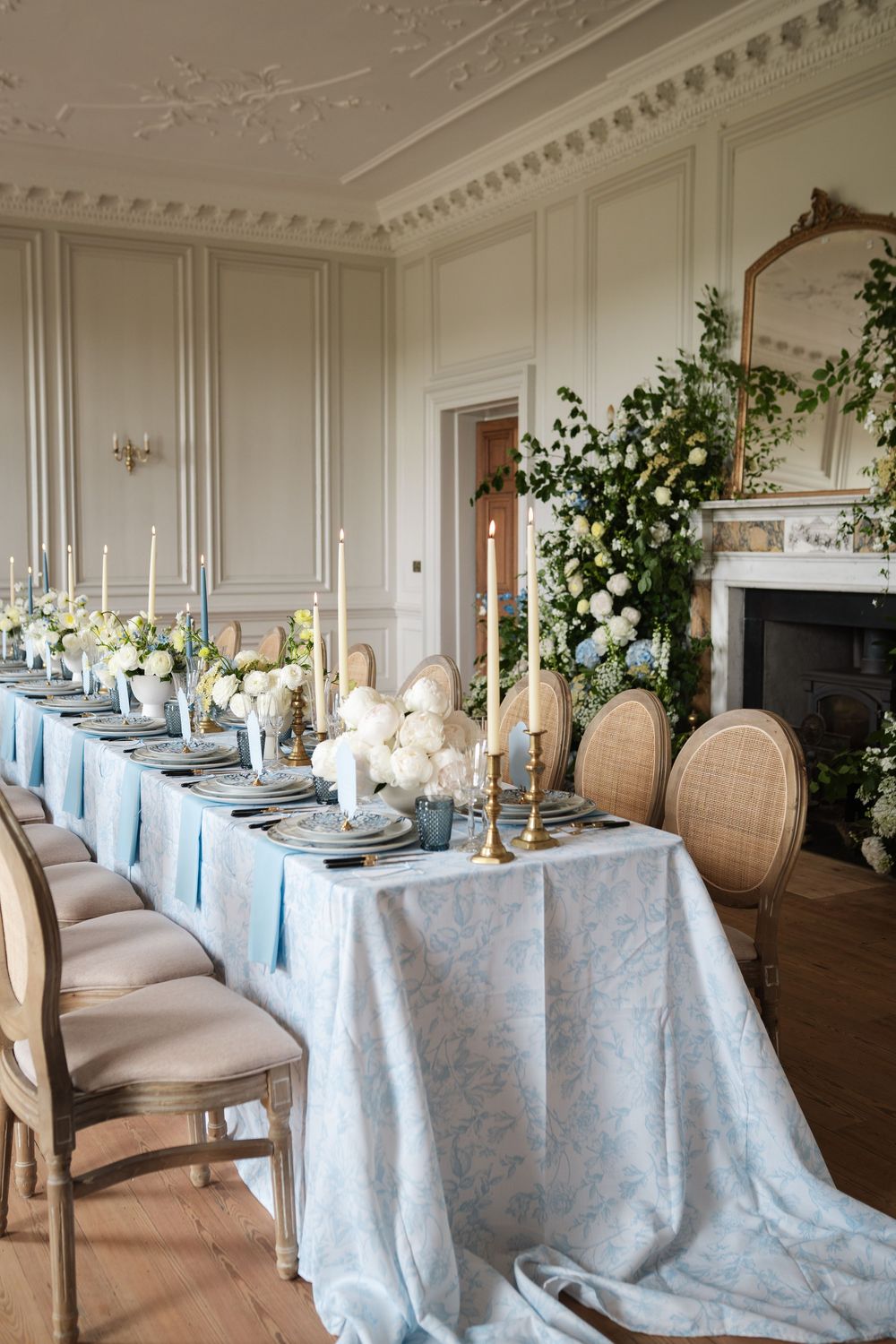 Elegant dining room with upholstered chairs and blue tablecloths set for a formal event.