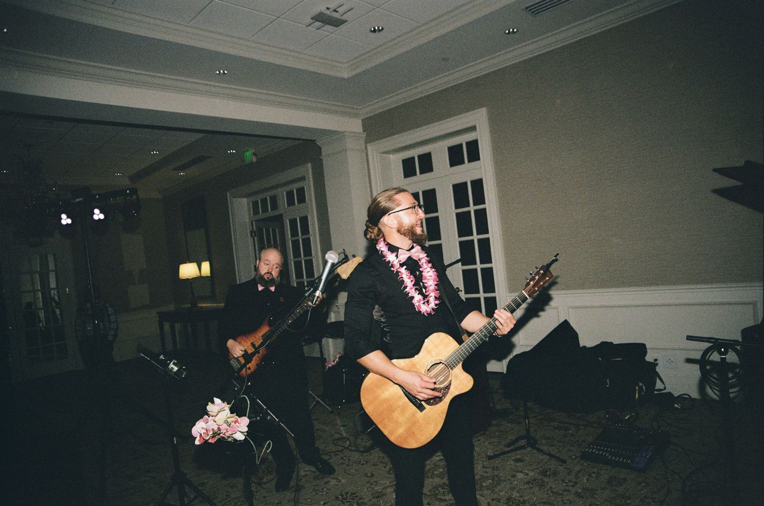 An acoustic guitarist performs solo at an indoor venue with dark lighting and white trim on the walls.