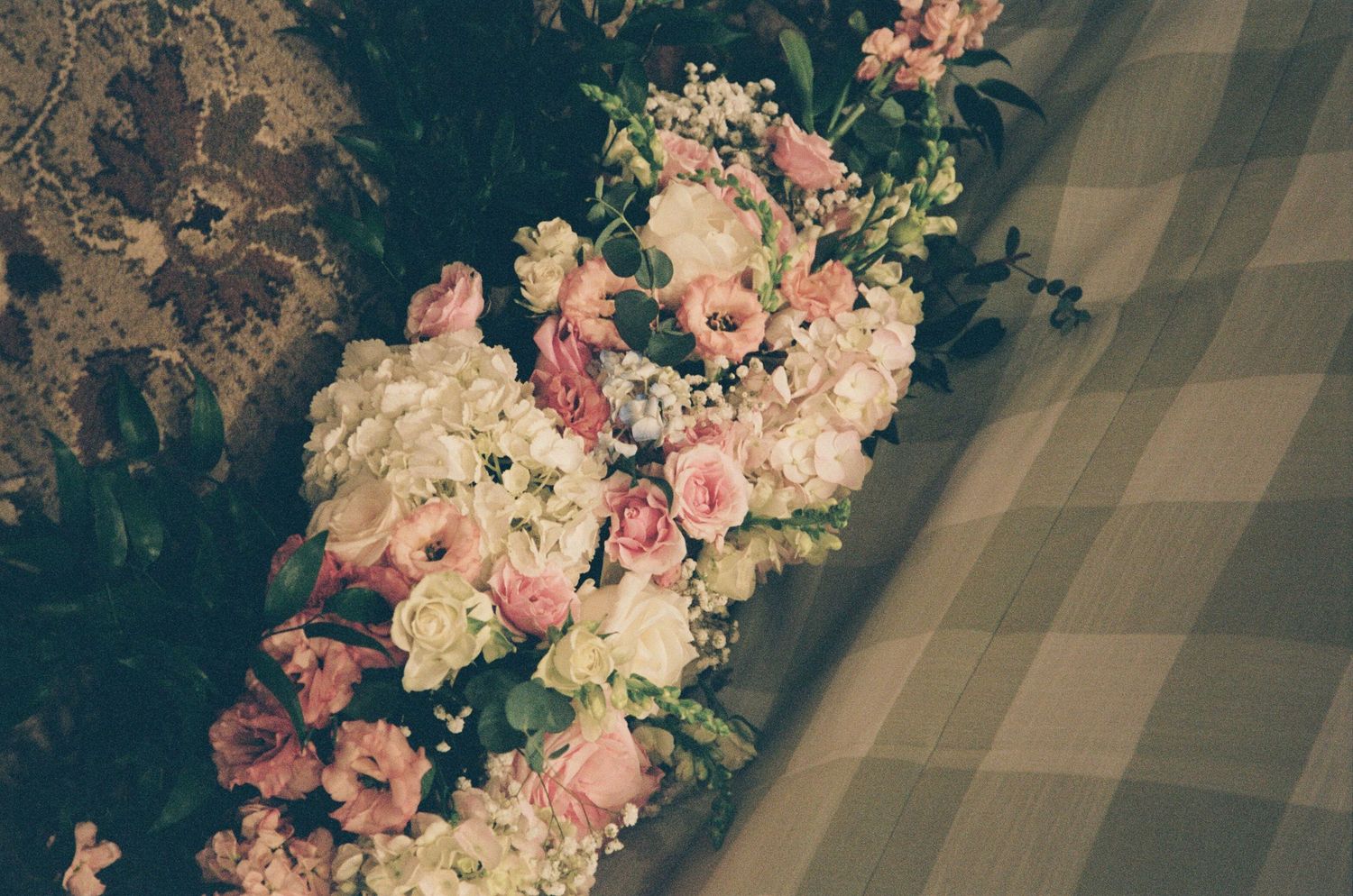An elegant floral arrangement with pink and white blooms displayed in multiple glass vases at a wedding reception.