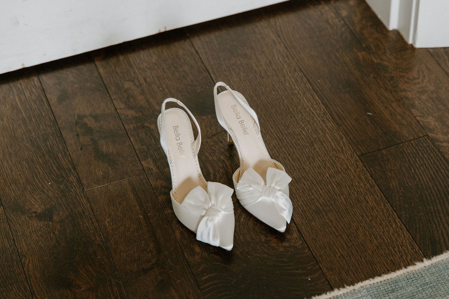 A row of gold metallic high heel shoes displayed on a dark rustic wooden floor.