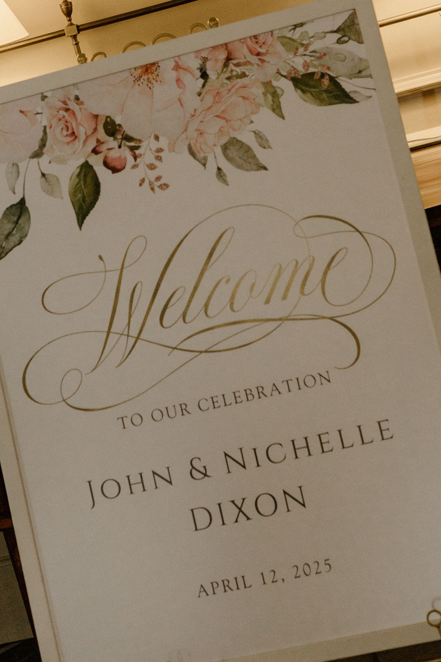 A wedding welcome sign with floral design features elegant calligraphy for John & Nichelle Dixon's celebration on April 12, 2025.