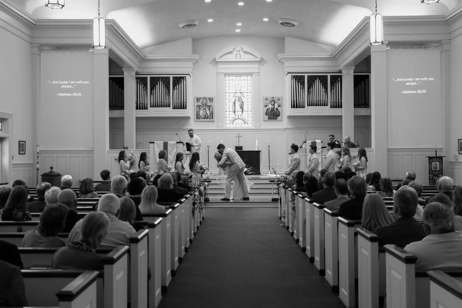 Black and white photograph showing congregation gathered in church pews during religious service inside traditional chapel.