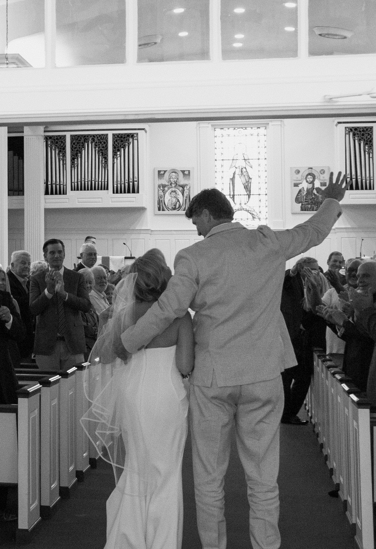 Black and white photo series showing progression as couple walks down church aisle during wedding ceremony.