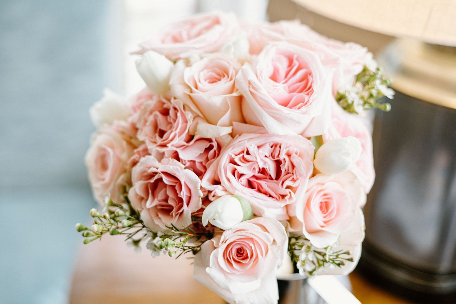 Delicate bouquet of light pink garden roses with baby's breath against a soft neutral background.